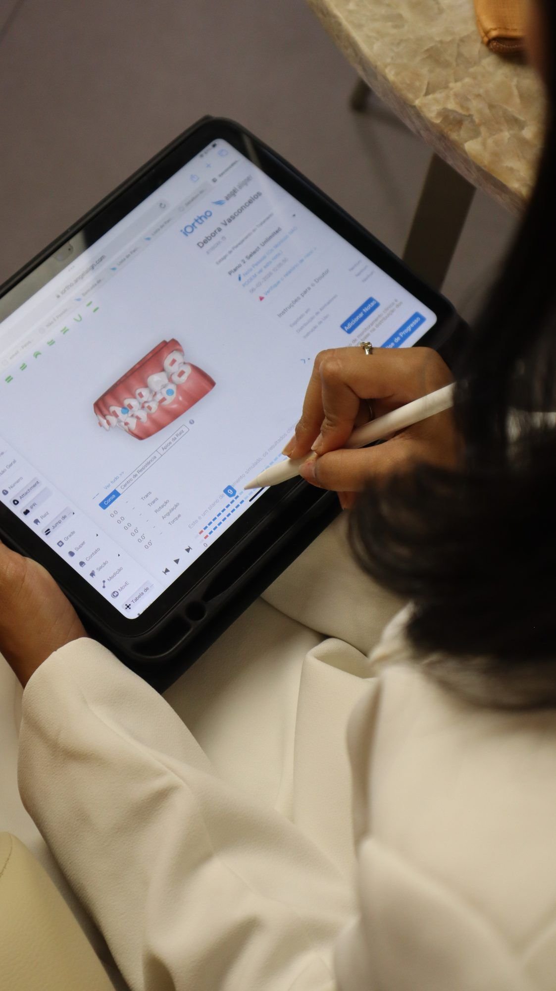 Planejamento ortodôntico digital em um tablet, com caneta sobre a tela.